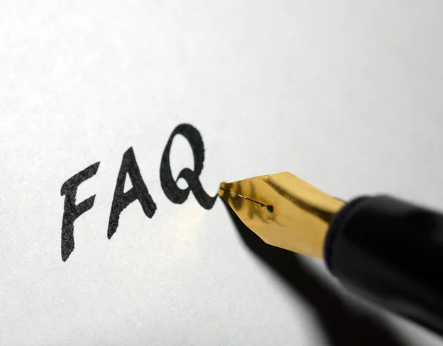 FAQ mit schwarzer Tinte auf einem weißen Papier geschrieben.